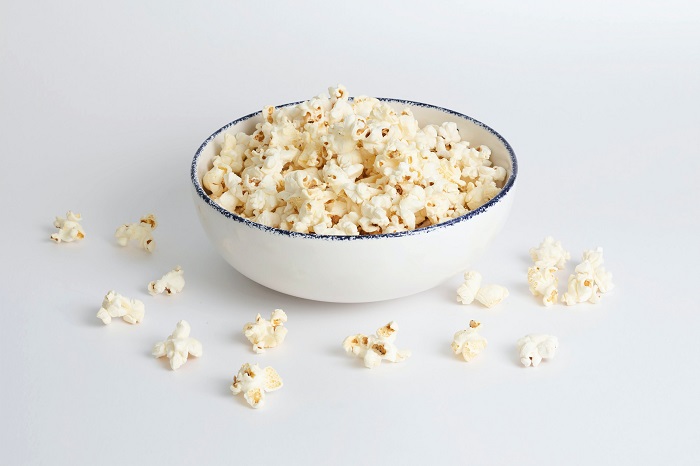 Curious cat drawn to a bowl of popcorn.