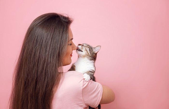 Photo of a cat gently licking a girl's hand, exemplifying a sweet and nurturing interaction between the cat and the child.