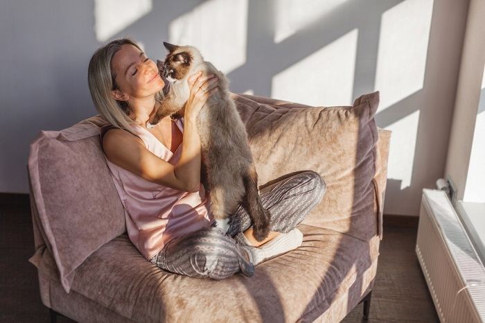 Cat tenderly licking its owner's hand, portraying a gesture of closeness and endearing companionship.