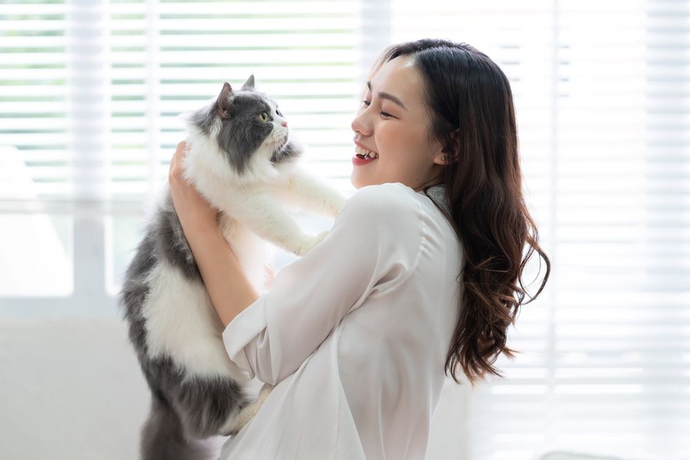 woman playing with cat at home