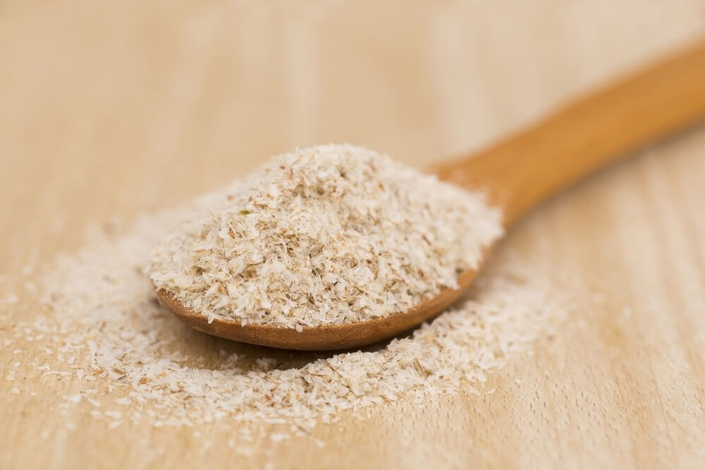 Wooden Spoon with psyllium seeds on wooden background